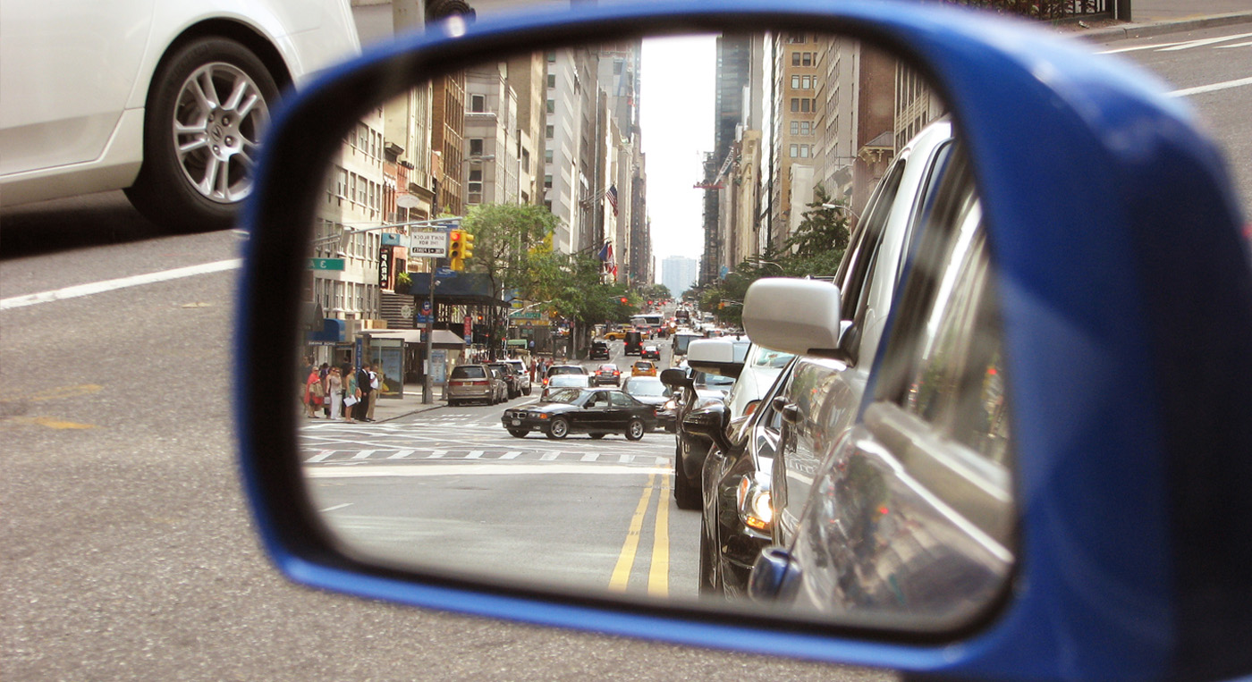 Close up photo of a side view mirror reflecting a downtown city street