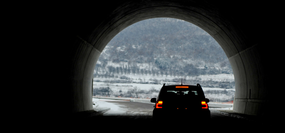 A car driving out of a darkened tunnel into the light.