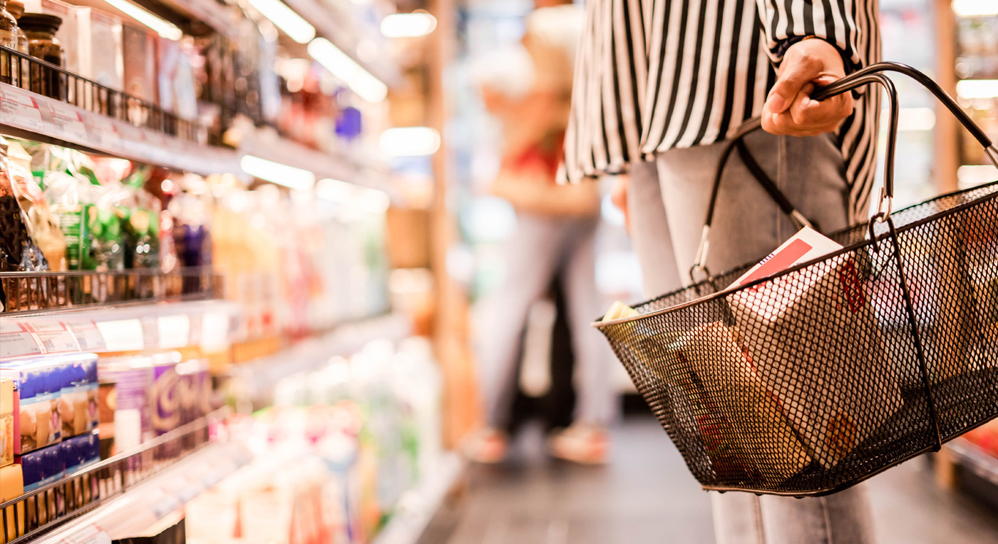 Shopper holding a basket in a grocery store