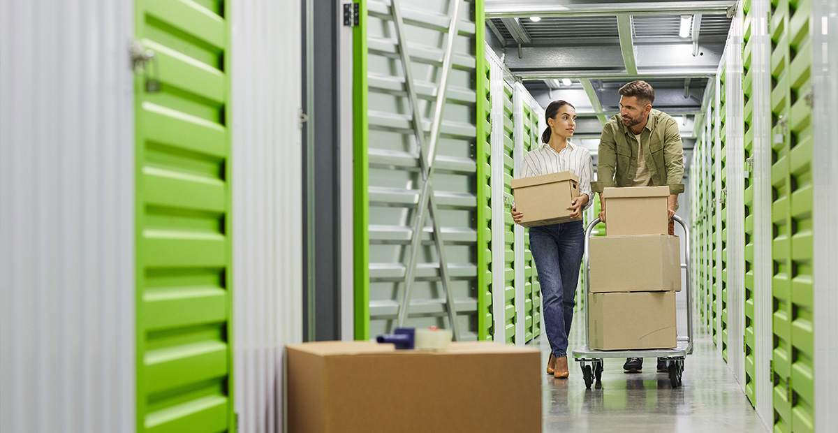 Two people carrying boxes in a self-storage facility