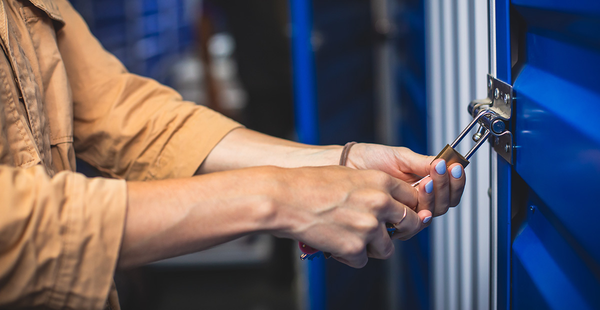 Someone adjusting a pad lock on the exterior latch of a storage unit