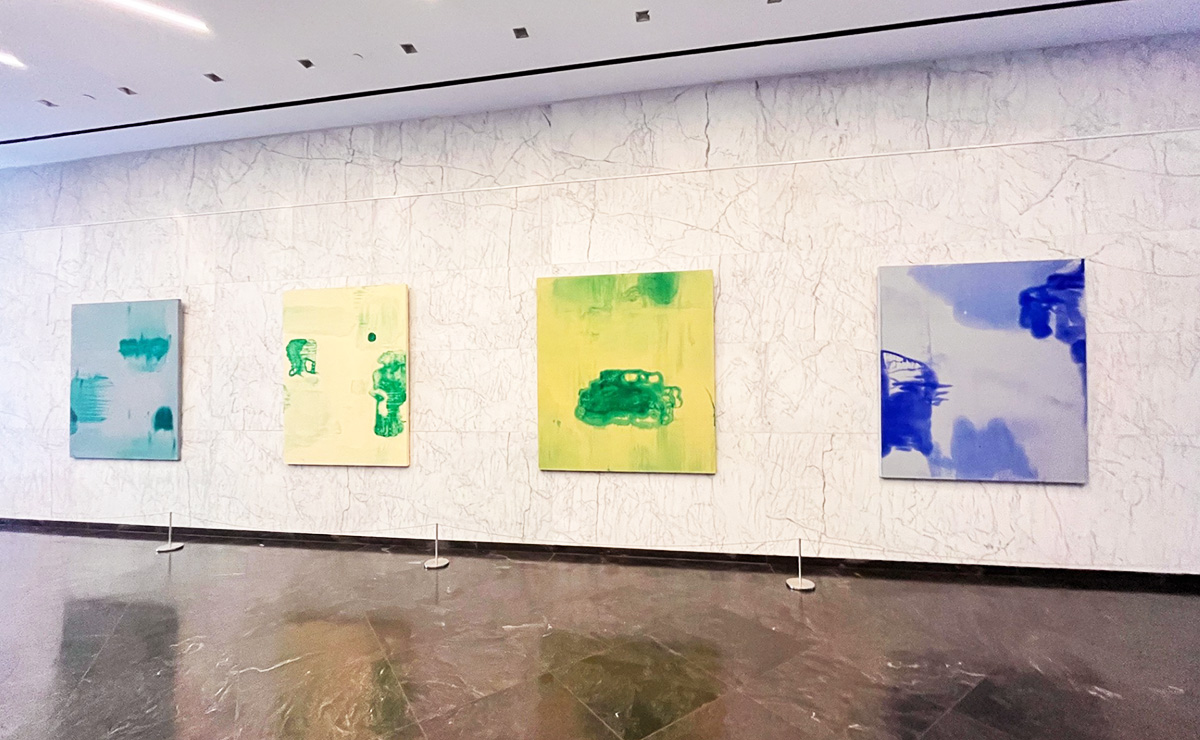 A row of abstract art pieces hanging on the wall in a lobby of a building